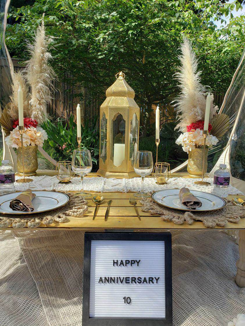 An anniversary tablescape with a gold lantern, pampas and taper candles