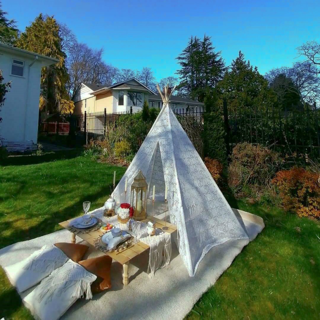 Lace teepee and low table picnic in a backyard under a clear blue sky