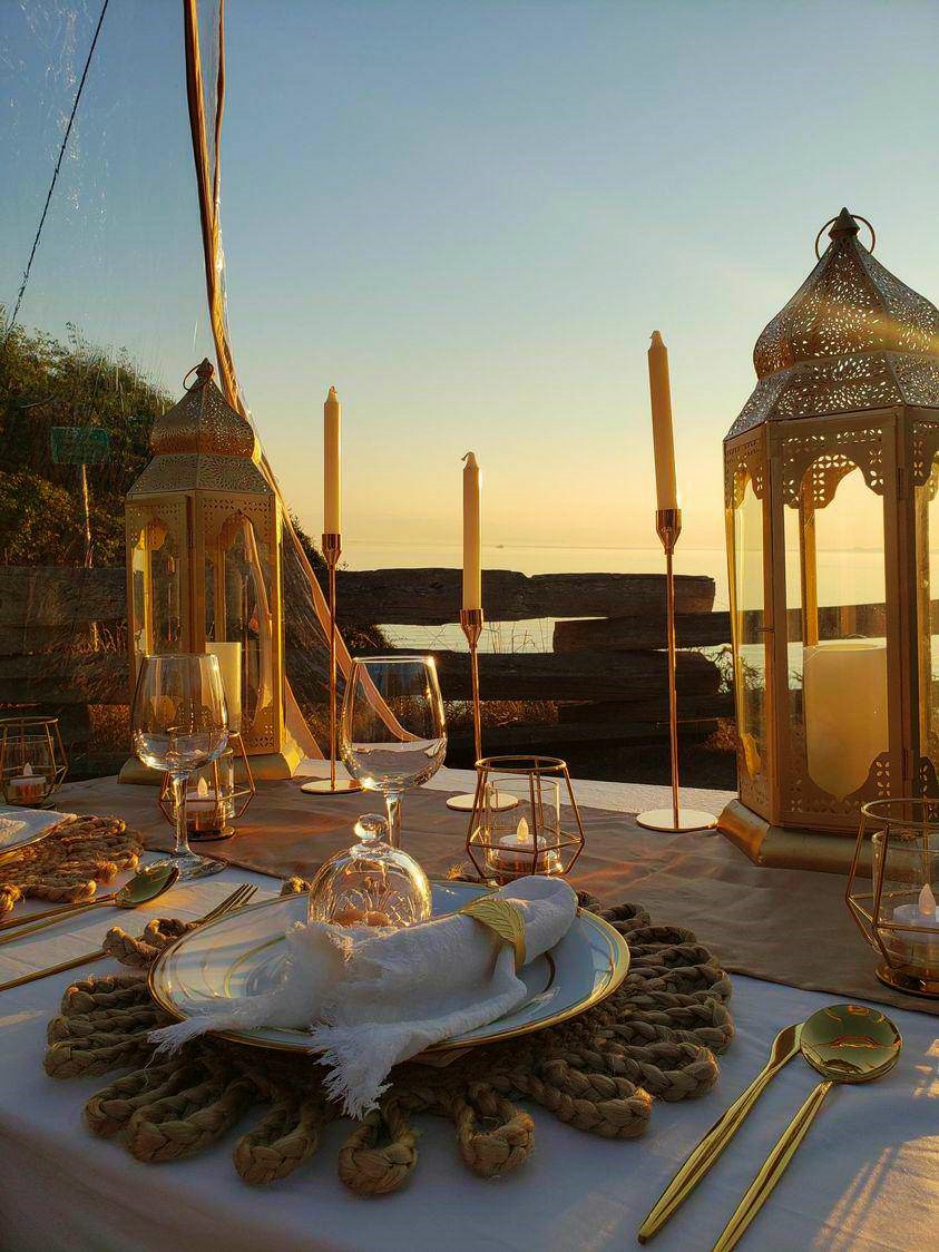 Candlelit dinner for two with gold Moroccan lanterns at sunset on a beach