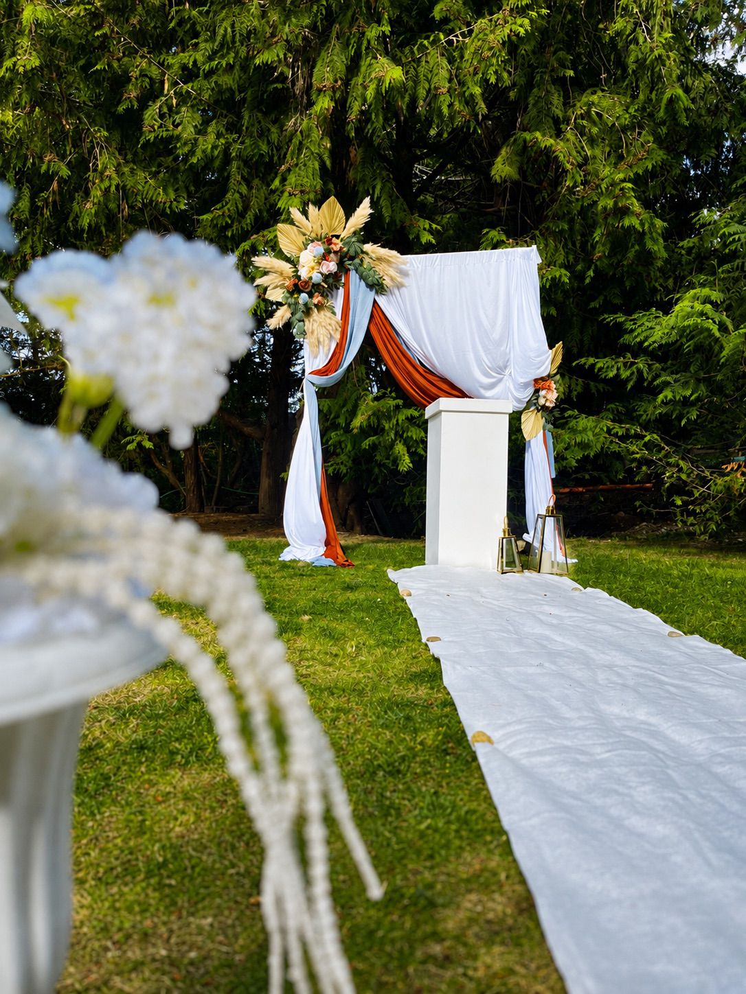A wedding ceremony aisle leading to a draped floral arch
