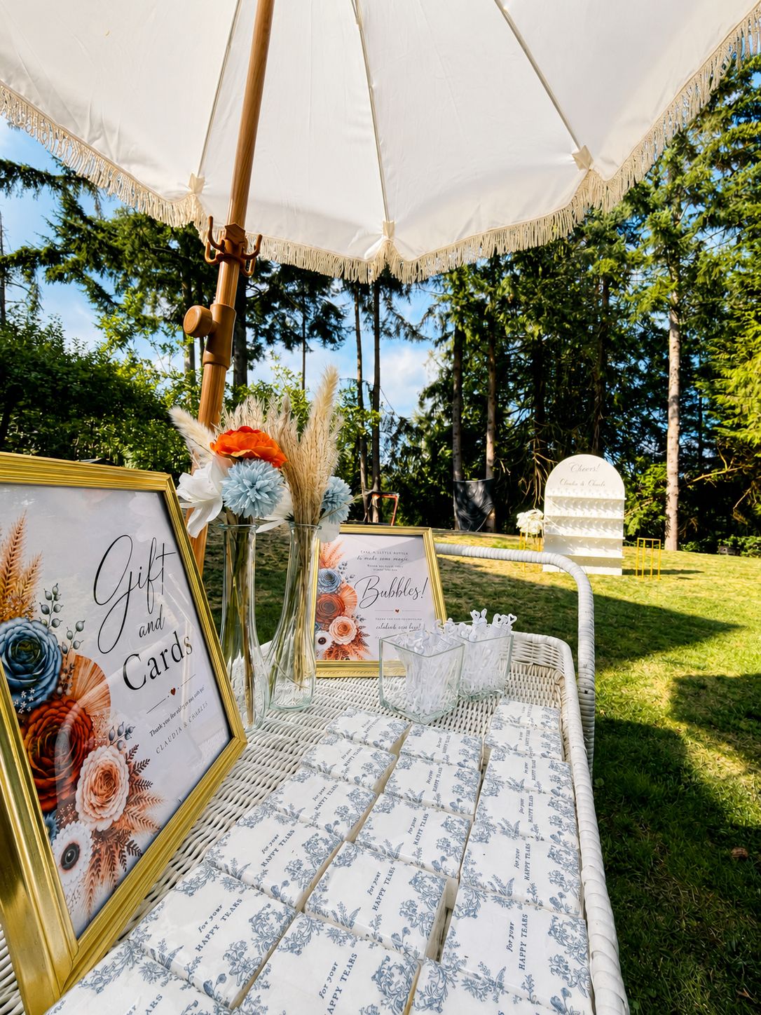 White bar cart with framed Bubbles and Gift and Cards signs under a fringe umbrella
