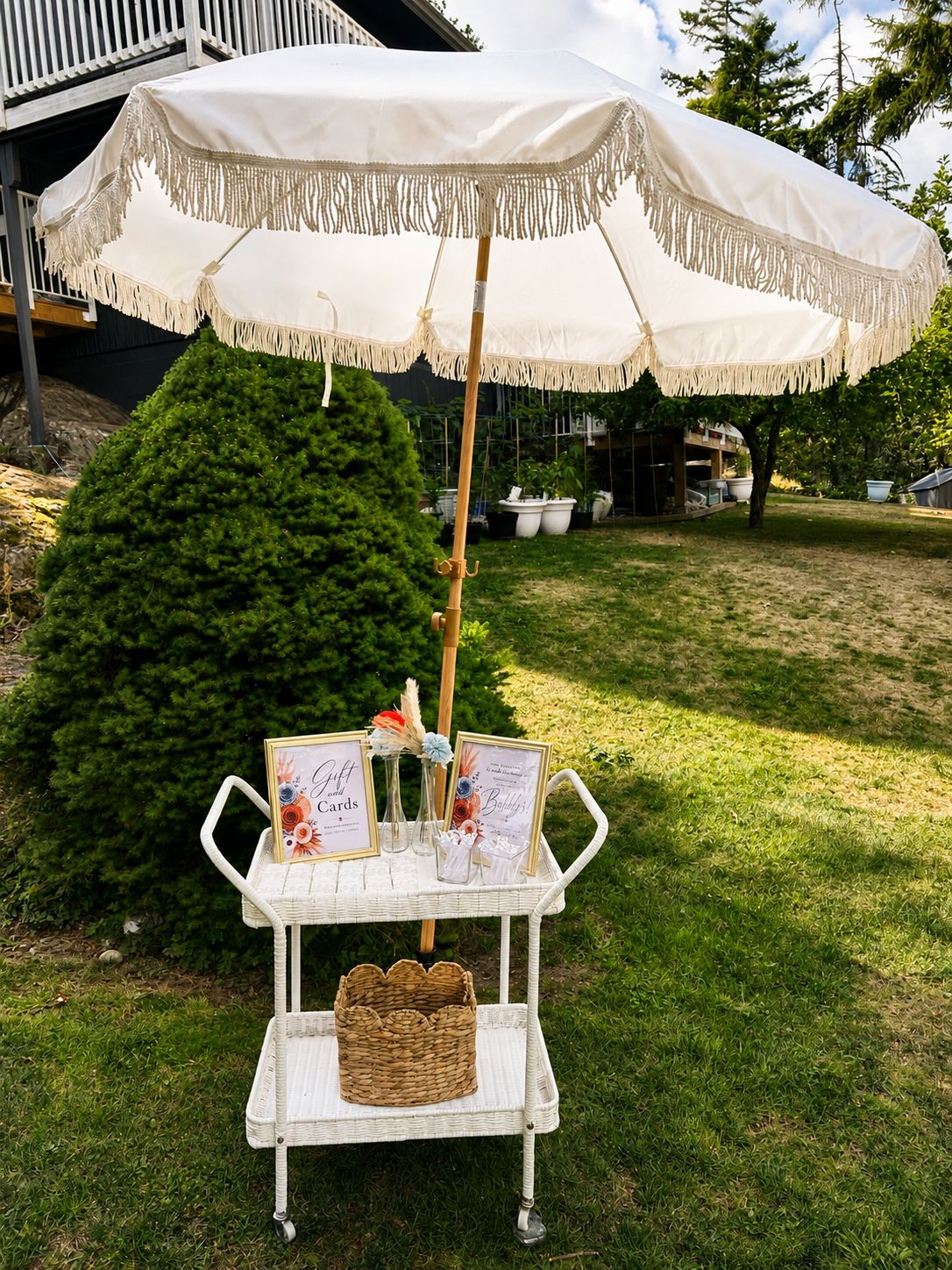 Gift and cards table under a cream fringe umbrella with framed signs and florals